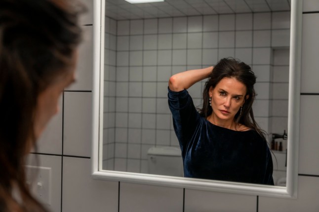 Demi Moore as Elisabeth Sparkle looking in a mirror in The Substance