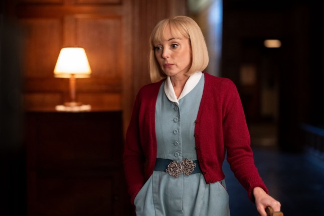 Helen George in Call the Midwife wearing a blue dress and red cardigan
