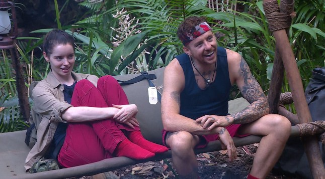 Maura Higgins and Danny Jones sit on log in scene from I'm A Celeb