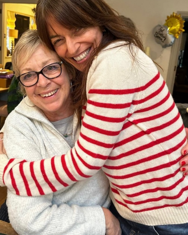 Davina McCall in a red and white striped jumper sits on the lap of her stepmum Gaby, giving her a hug, in a recent photo
