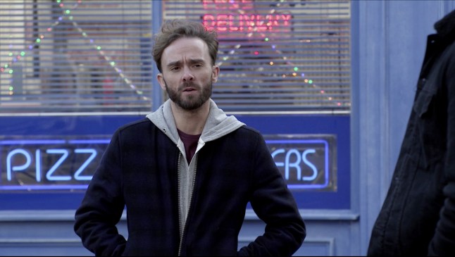 David Platt looking wary with his hands in his pockets outside Prima Doner in Coronation Street.