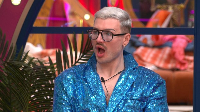 Danny Beard on Celebrity Big Brother wearing a sparkly blue top and glasses, and looking shocked
