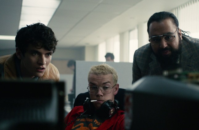 Fionn Whitehead as Stefan Butler, Will Poulter as Colin Ritman and Asim Chaudhry all crowded around a computer in Black Mirror: Bandersnatch
