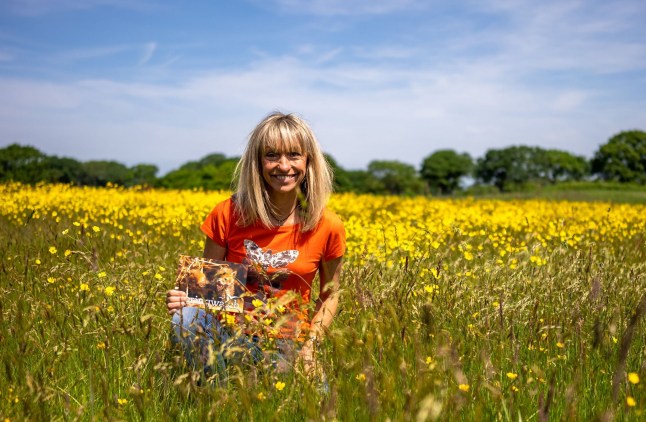 A faraway shot of Michaela Strachan in an orange top crouched down in a field of yellow flowers