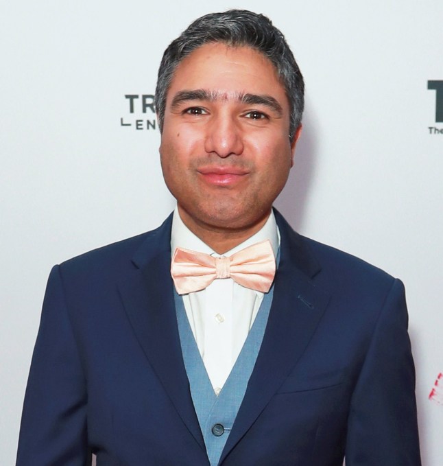 Close up of Nick Mohammed in a blue suit and pink bowtie
