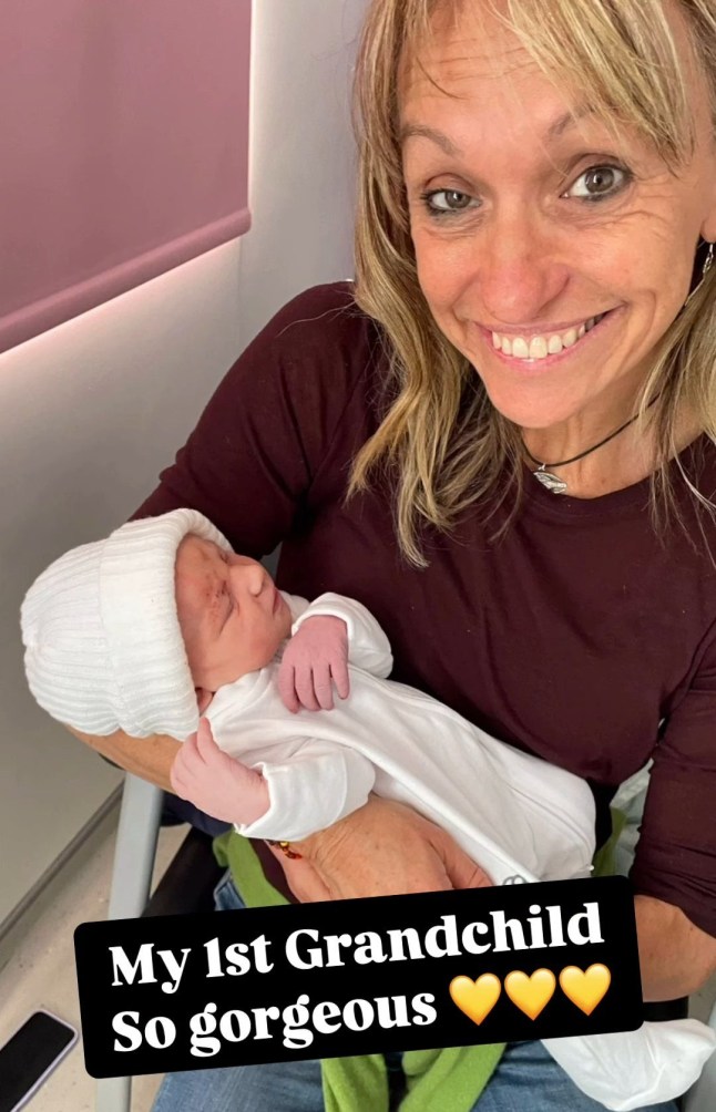 Michaela Strachan sat on a sofa holding a newborn baby with a black background caption over the image reading: 'My first grandchild, so gorgeous'