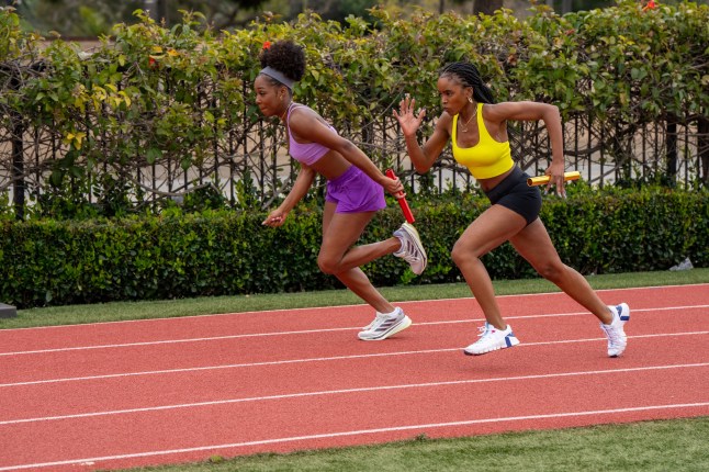 Two teen girls in running outfits race each other on a school race track