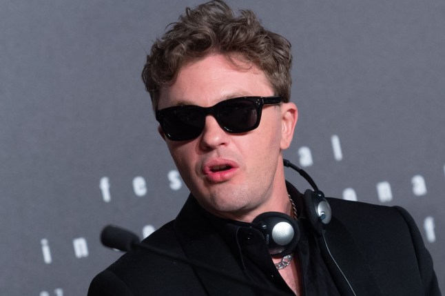 Michael Pitt in sunglasses amd with headphones around his neck attends the press conference for Black Flies at Palais Des Festivals in Cannes, France